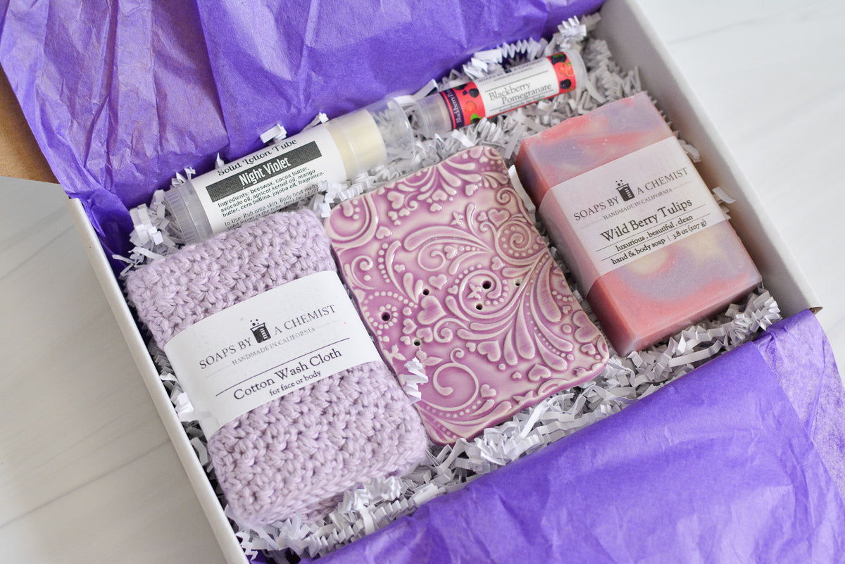 purple mother's day gift set with handmade ocean soap, ceramic soap dish, cotton crocheted wash cloth, lip balm, and solid lotion tube. side view